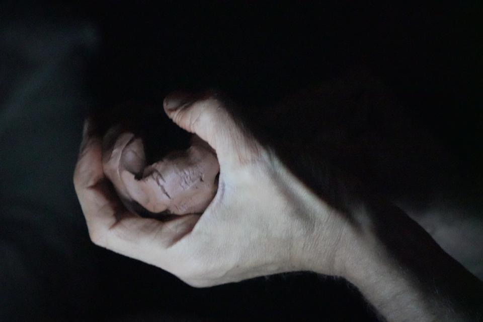 hand holding a bowl of clay