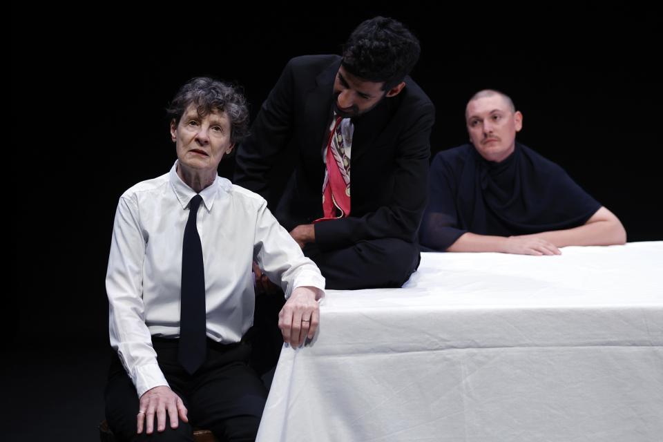 Three actors sitting at a table, one crying