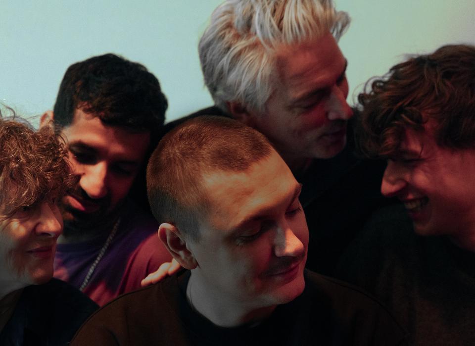 Louis surrounded by the cast, all with their eyes closed