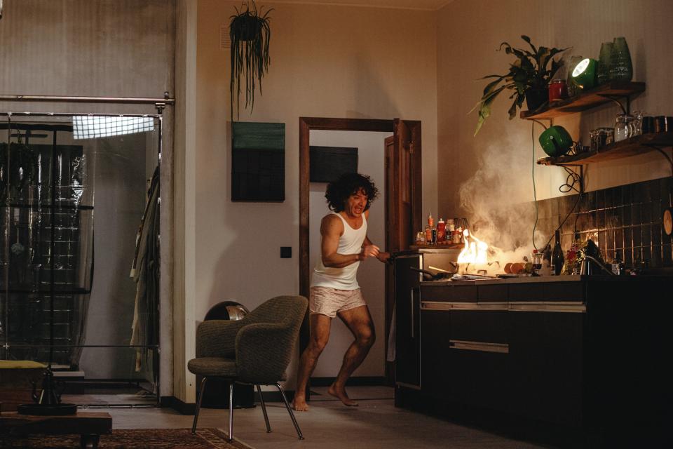 A person in their underwear holding a burning pan