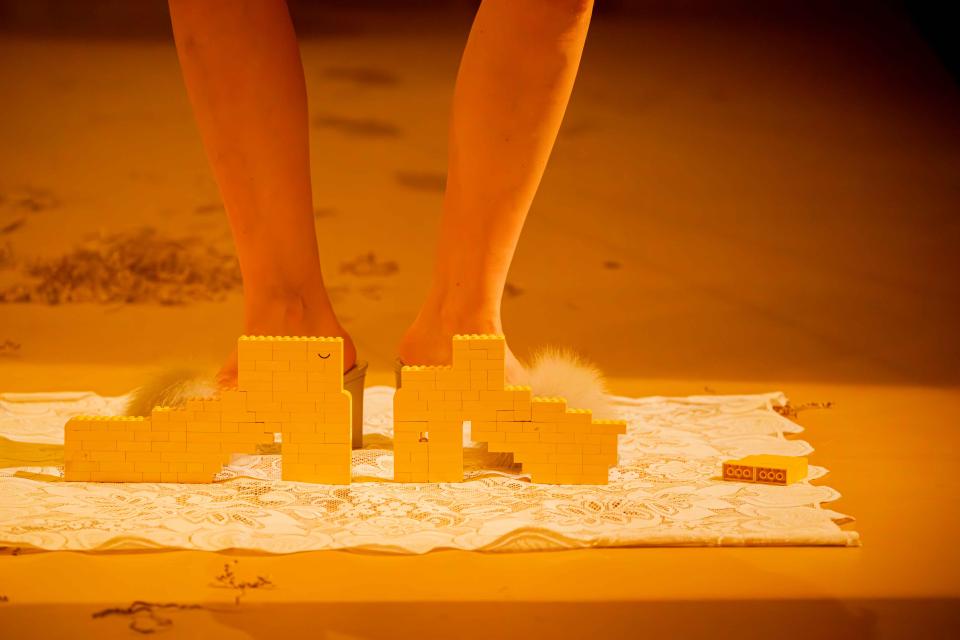 Someone posing behind two shoes made of Lego