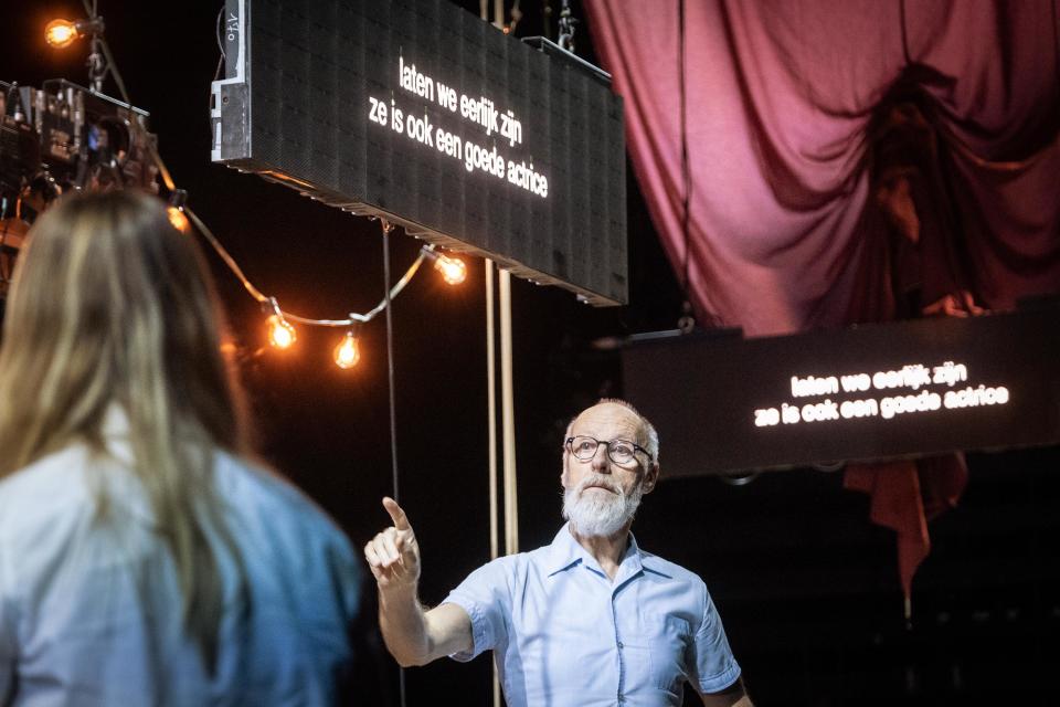An actor with his index finger up in front of screens that read "laten we eerlijk zijn, ze is ook een goede actrice"