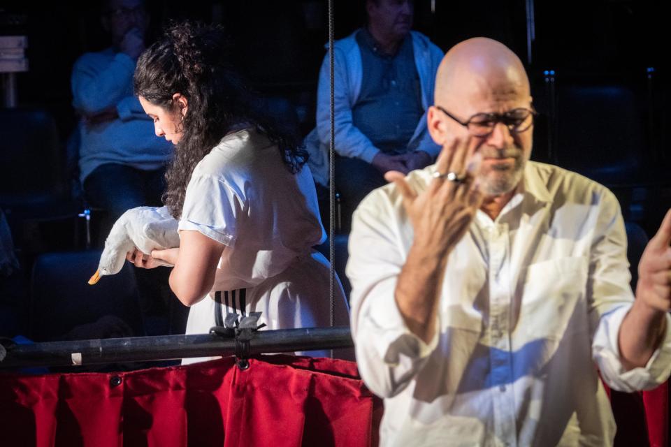 An actor signing and another actor holding a seagull in the background
