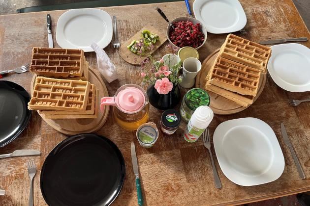 A table with waffles, toppings and plates